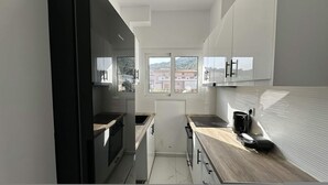 A compact kitchen with a built-in oven, a stovetop, and a coffee machine. - Loutra Suites Aegean Wave Suite (Corinth)