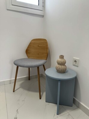 Un coin avec une chaise, une petite table et un vase.