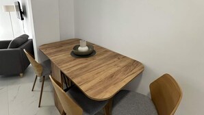 Ein Essbereich mit einem Holztisch, vier Stühlen, einer Schüssel und einer Wandleuchte.