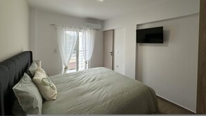 Ein Schlafzimmer mit Bett, Vorhängen, einem Fernseher und einer Klimaanlage.