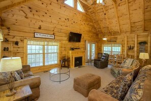 A log cabin interior with a fireplace, a television, and a cozy seating area. - Mountain Paradise: Free Tickets/ Mnt Views (Sevierville)