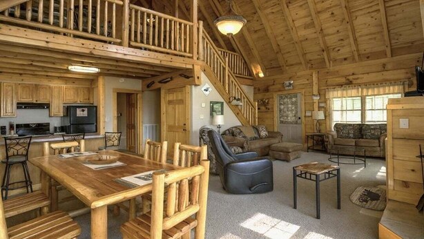 A spacious cabin with a dining area, kitchen, and living room. - Mountain Paradise | Mtn View, Hot Tub + FREE Tickets (Sevierville)