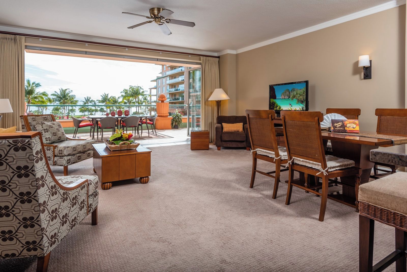 Ein Hotelzimmer mit Balkon, Essbereich und Fernseher.