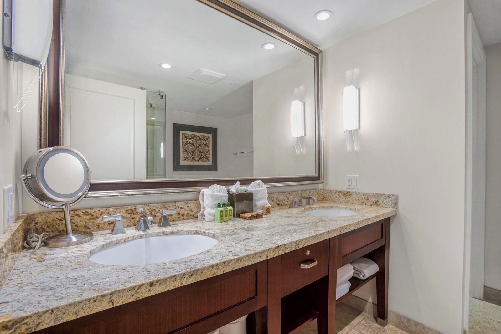 Une salle de bain avec deux lavabos, un grand miroir et un meuble-lavabo doté d’un porte-serviettes.