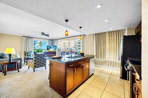 Habitación de hotel moderna con isla de cocina, comedor y vista al océano.
