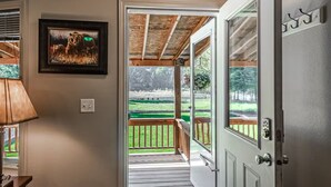 A hallway leading to a deck with a view of a grassy area.