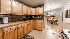 A kitchen with wooden cabinets, a microwave, a toaster, and a dining area with a table and chairs.