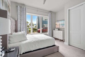 Ein Schlafzimmer mit Bett, Fernseher, Kommode und einer Schiebetür zum Außenbereich.