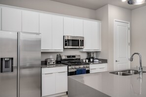 A modern kitchen with stainless steel appliances, white cabinetry, and a built-in oven. - Golf-View Reunion Condo Near Disney | Pool & Gym (Kissimmee)
