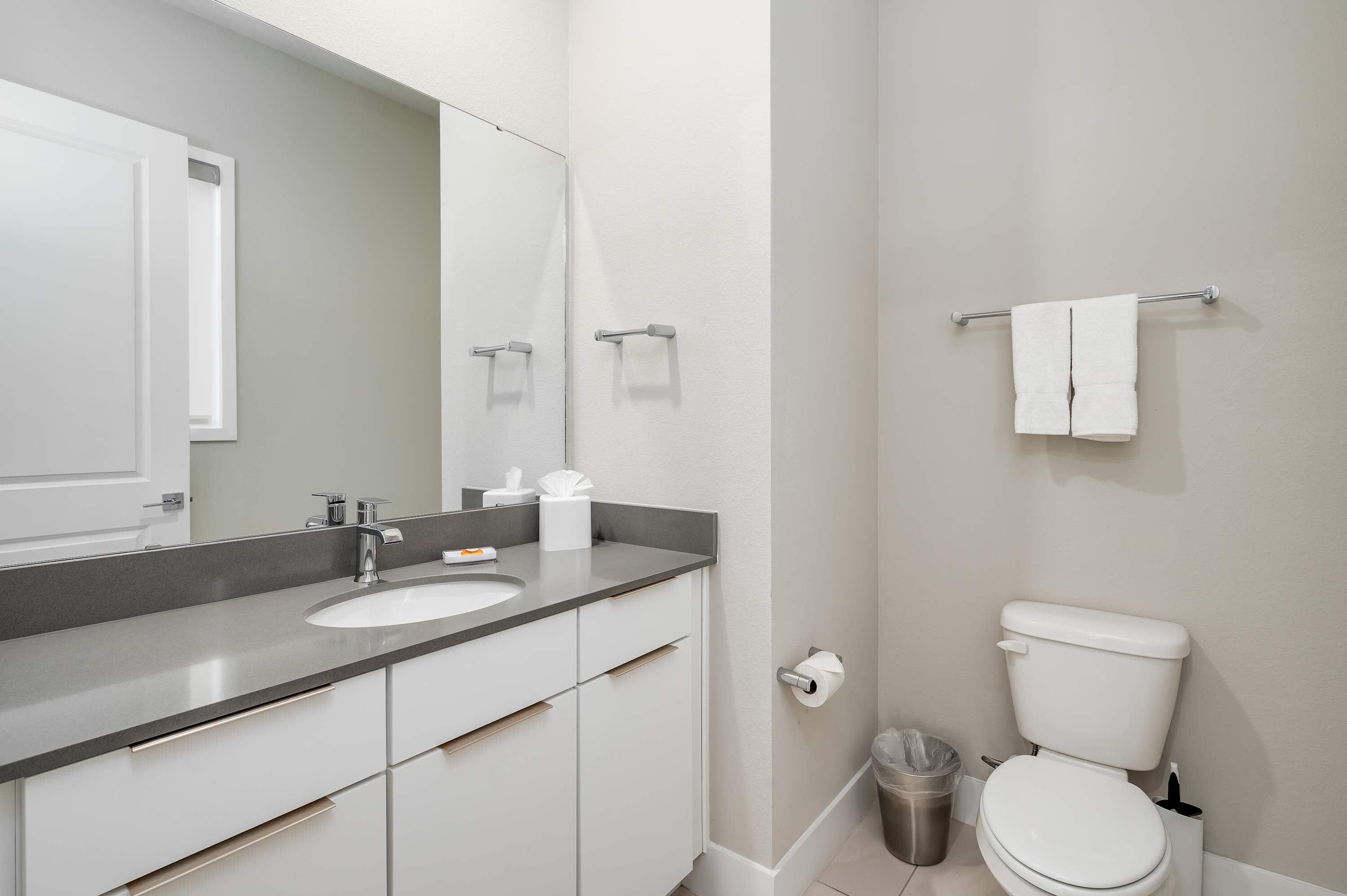 A modern bathroom with a white sink, mirror, and toilet.