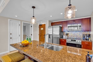 A modern kitchen with granite countertops, stainless steel appliances, and pendant lighting. - 4 Honua Kai Villas | Ocean Front | Sleeps 26 | Free Car w/ 6+ Nights | ML-3179 (Lahaina)