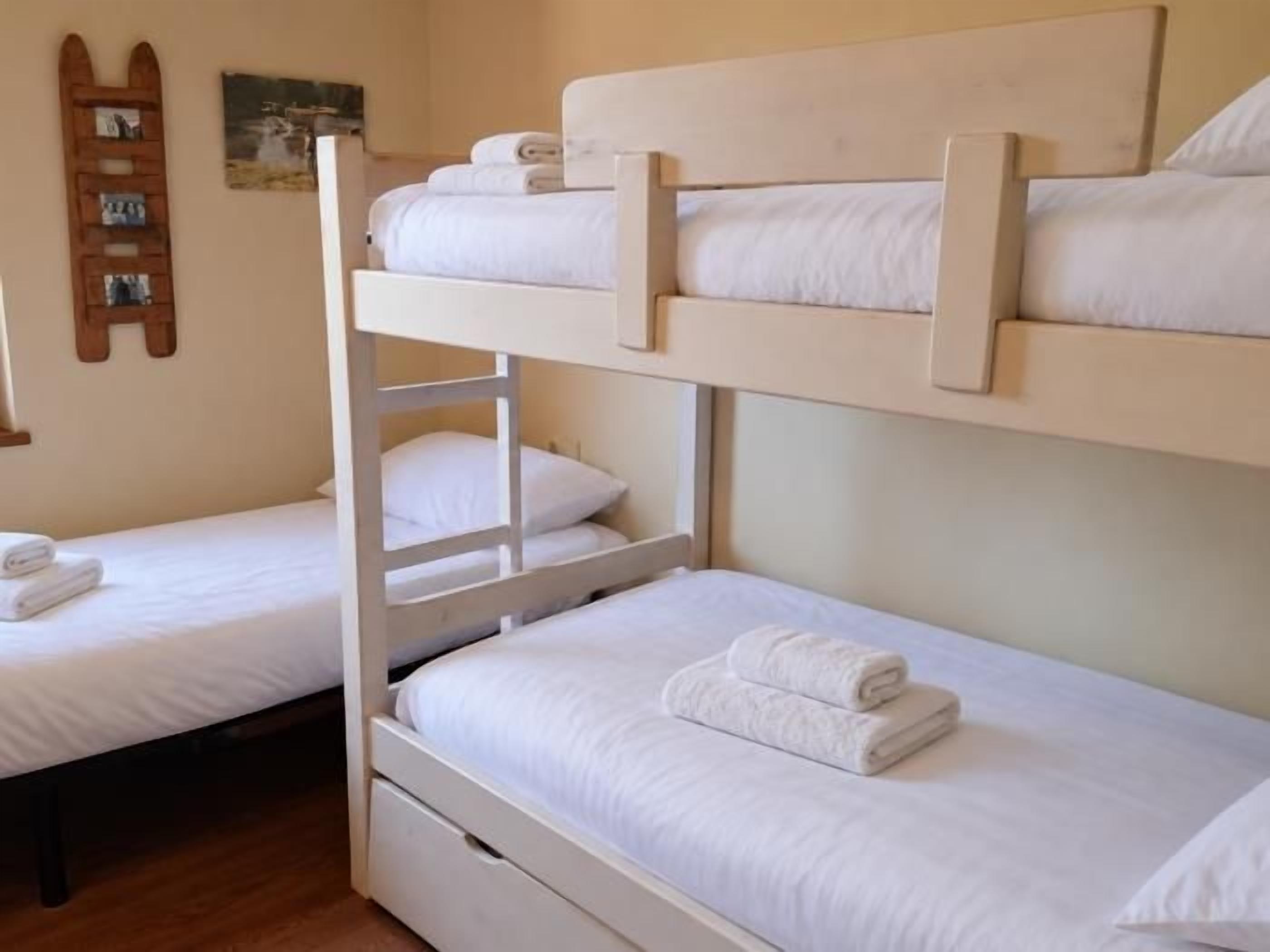 Habitación con literas, una pequeña repisa y estantes fijados a la pared.