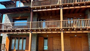 Un edificio in legno su più piani, con balconi, pareti in pietra e ampie porte in legno.