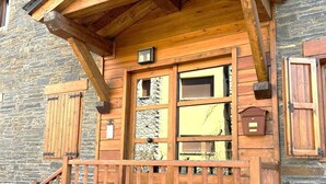 Un edificio in legno con facciata in pietra, un balcone in legno e una finestra con persiane.