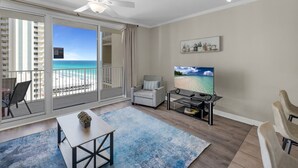 Sala de estar moderna com varanda, TV de tela plana e vista para a praia.