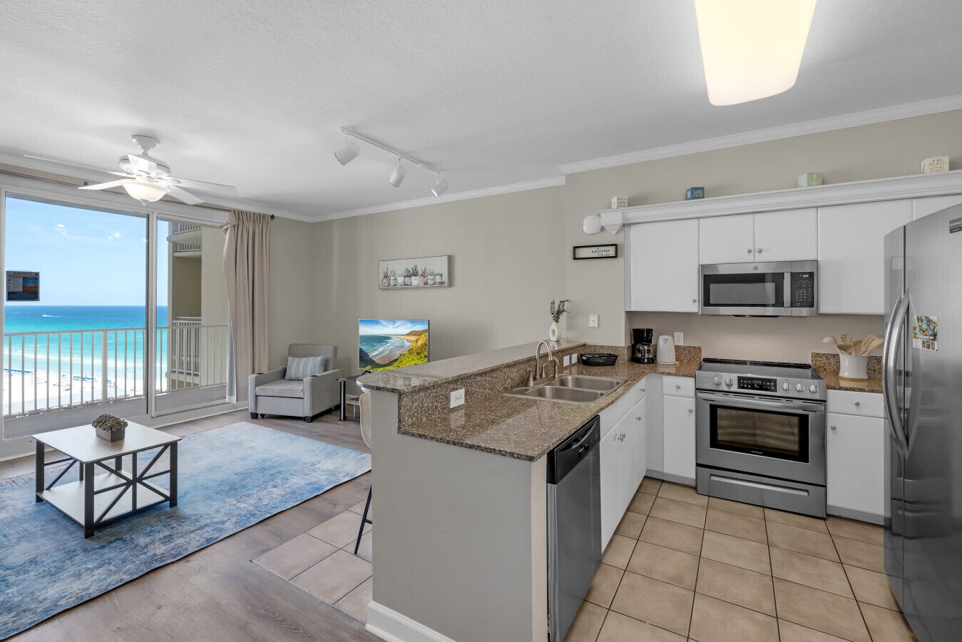 Een moderne keuken met een ingebouwde oven, magnetron en koelkast, een zithoek met tafel en stoelen, en een balkon met uitzicht op de oceaan.