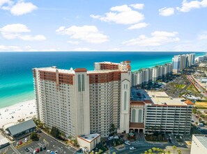 Ein Hochhaus-Hotel mit Blick auf den Strand, mehreren Etagen und einem Parkplatz.