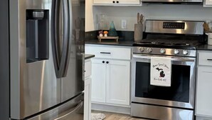 Una cocina moderna con electrodomésticos de acero inoxidable, armarios blancos y suelo de madera.