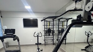 Un gimnasio con equipo de ejercicio, cinta de correr y un espejo que refleja el espacio.