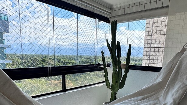 Una hamaca en una habitación con vistas a un cactus y un paisaje lejano.
