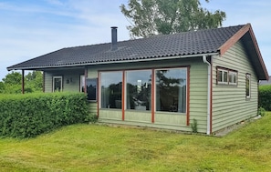 Une maison de plain-pied avec un toit en pente, de grandes fenêtres et une cheminée.
