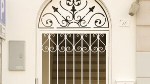 Une porte blanche ornée d’une grille métallique décorative et d’une enseigne indiquant « SPAGNOLO BED & BREAKFAST ».
