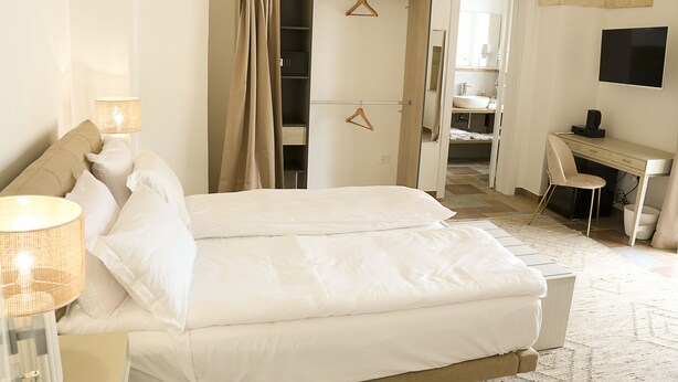 Une chambre à coucher comprenant un lit, une lampe de chevet, une armoire, un bureau, une chaise et un téléviseur.