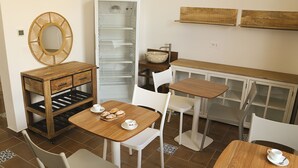 Une cuisine avec une table en bois, des chaises blanches, un réfrigérateur et un meuble en bois.