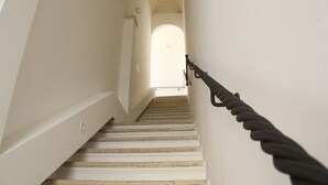Un escalier muni d’une rampe, menant à une porte en arc de cercle située en haut.