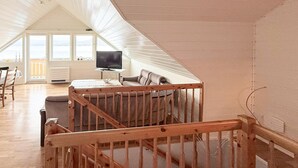 Ruime loft met hoge plafonds, een houten trap, een flatscreen-tv en uitzicht op de omgeving.