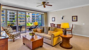 Ein geräumiges Wohnzimmer mit Sofa, Sesseln, Couchtisch und Deckenventilator.