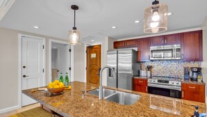 Eine moderne Küche mit Granit-Arbeitsplatten, Edelstahlgeräten und Pendelleuchten.