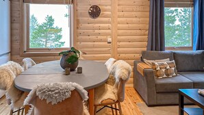 L’intérieur d’un chalet accueillant, avec une table ronde, un canapé et une horloge au mur.