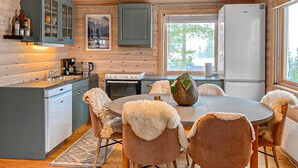 Un intérieur de chalet chaleureux avec une cuisine, un coin repas et une grande fenêtre.
