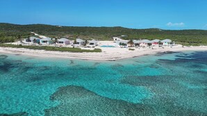 Une propriété située sur la côte, comprenant plusieurs bâtiments, une plage et des eaux turquoise cristallines.