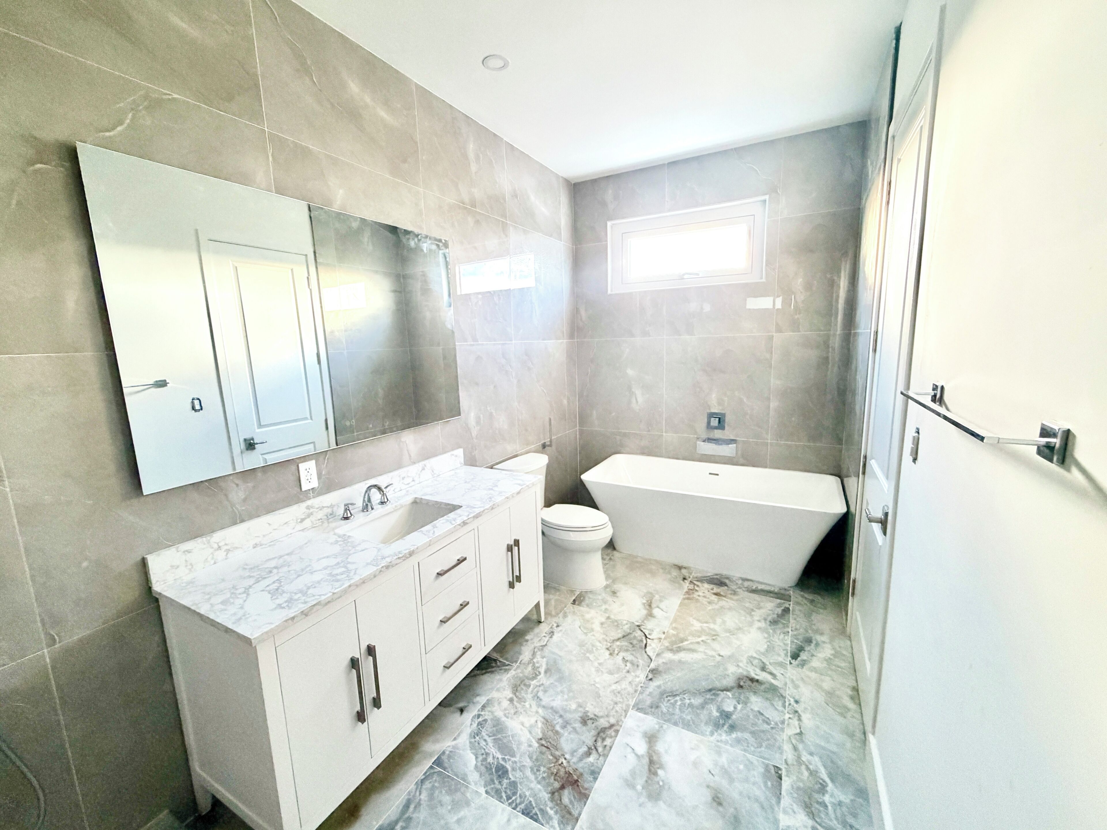 Un baño moderno con lavamanos de mármol, inodoro y bañera.