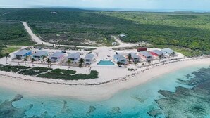 Vue aérienne d’un complexe hôtelier comprenant plusieurs bâtiments, une piscine et une plage.