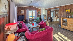 Ein gemütliches Wohnzimmer mit Kamin, Holzwänden und einem Fernseher.