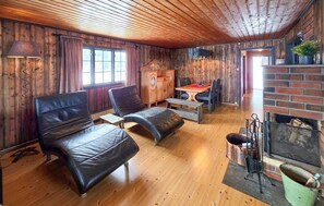 A cozy room with wooden walls, a fireplace, a dining table with chairs, and leather seating. - 3 bedroom gorgeous home in Vinje (Vinje)