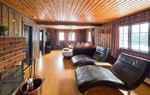 Un salon chaleureux avec une cheminée, des canapés en cuir et un plancher en bois.