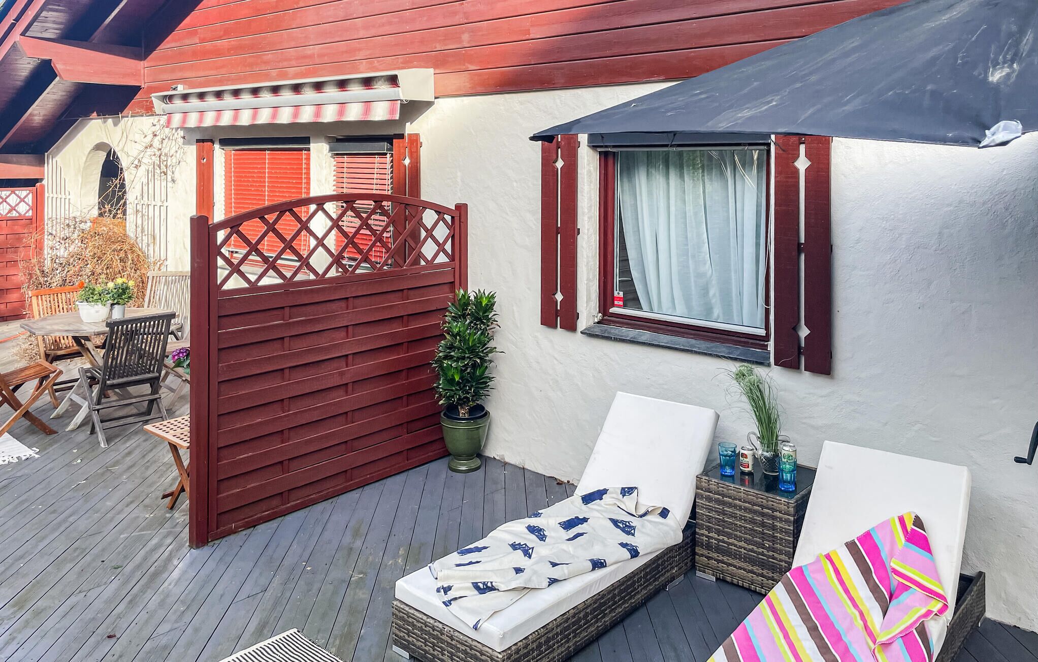 Ein Balkon mit Liege aus Rattan, einem kleinen Tisch und einem Blumentopf.
