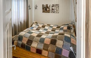 Un llit amb llençols de quadres, un capçal de fusta i una paret amb quadres emmarcats.
