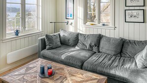 En grå soffa med ett vitt element, ett soffbord med ljus och inramade tavlor på väggen.