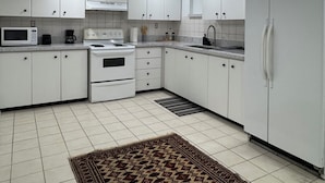 A modern kitchen with white cabinets, a stove, microwave, and refrigerator.