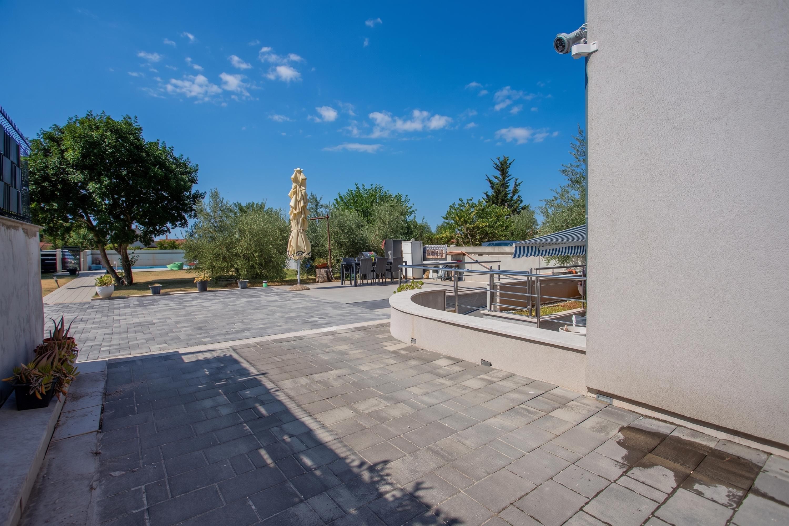 Un patio al aire libre con un camino empedrado, mobiliario para sentarse y vistas al cielo.