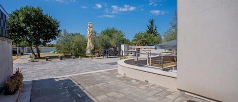 An outdoor patio area with a paved walkway, seating arrangements, and a view of the sky.