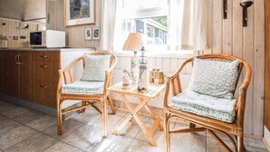 A room with two wicker chairs, a small table, a lamp, a framed picture on the wall, and a window with curtains. - Pet friendly home in Tarm with WiFi (Tarm)