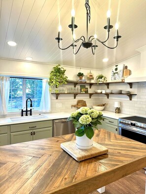Una cocina con una isla de madera, iluminación colgante y estanterías empotradas.