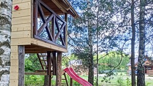 Una casetta giocattolo in legno con uno scivolo e un contenitore blu.