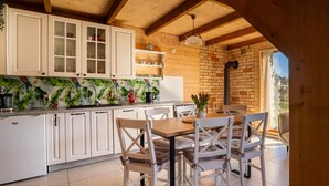 Una cucina con mobili bianchi, soffitto in legno e vista all'esterno.